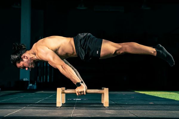 Man performing a controlled bodyweight exercise on a mat in a minimalist room.